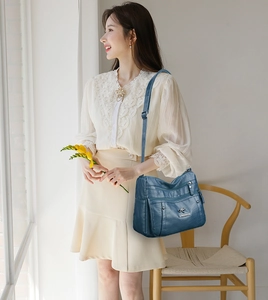 Close-up of a dark blue PU leather shoulder bag with multiple zippers and gold-tone hardware