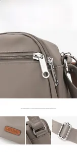 Detail of silver zippers and branded leather logo on taupe nylon crossbody bag