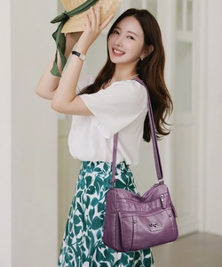 Close-up of purple soft PU leather shoulder bag with multiple zippers and adjustable strap