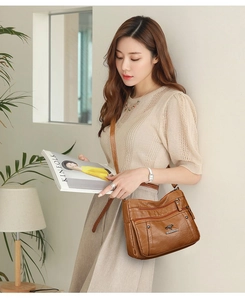 Detailed close-up of dark brown PU leather crossbody bag with multi-layer zipper pockets