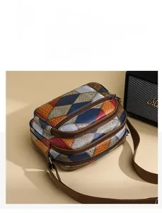 Detail of color-block crossbody bag with three zipper compartments and crocodile texture