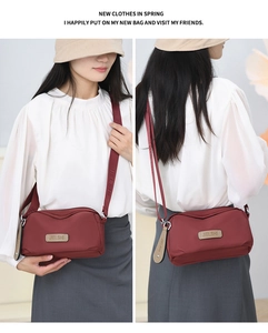 Detailed view of dark red nylon crossbody bag with adjustable wide shoulder strap