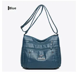Detail of blue textured leather shoulder bag featuring multi-zipper pockets and metal logo