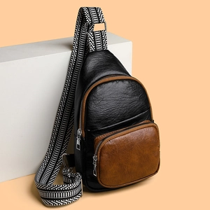 Minimalist black and brown leather crossbody chest bag with geometric woven strap on a pedestal