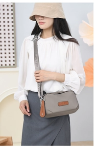 Detailed view of gray oxford crossbody bag with JIELSHI logo strap on a model