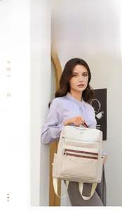 Detail of a beige faux leather backpack with multiple zip pockets and brown trim accents