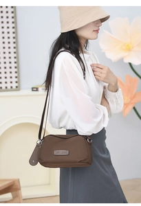 Brown nylon crossbody bag shown on model in a casual lifestyle setting