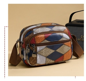 Macro view of multi-pocket crossbody bag with color-block panels and crocodile texture