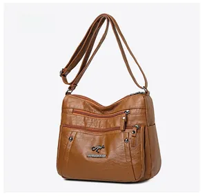 Detail view of the brown PU leather bag's texture and multiple zipper pockets