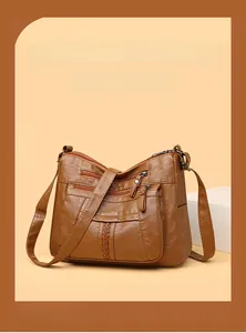 Detail view of brown washed leather crossbody bag with multiple zipper pockets and V-shaped stitch