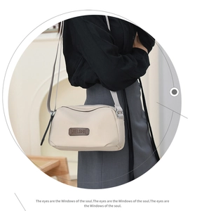 Close-up of beige waterproof crossbody bag featuring a classic brand logo and fabric strap