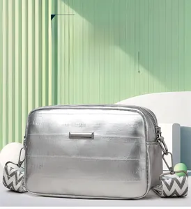 Silver metallic crossbody bag with textured patterns and a wide zigzag shoulder strap