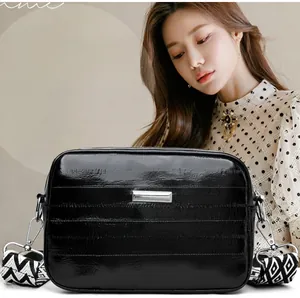 Detail of silver metallic textured crossbody bag with a geometric wide fabric strap