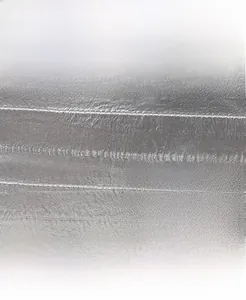Close-up of silver textured leather bag featuring precise stitching and polished metal plate