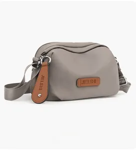 Side view of grey waterproof oxford shoulder bag showing zipper layers and logo