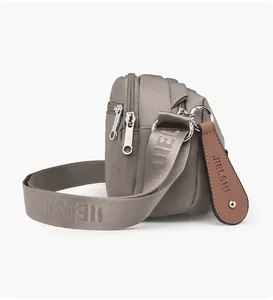 Detail of water-resistant oxford shoulder bag featuring layered zipper pockets and straps
