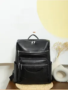 Detail of a black multi-pocket leather backpack on a desk with dry flower decor