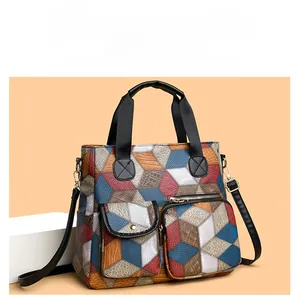 Detail view of colorful geometric patchwork pattern and front pockets on faux leather handbag