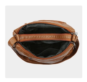 Top view of multi-compartment brown washed leather crossbody bag with silver zippers