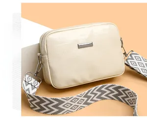 Detail of off-white crossbody bag with wide geometric strap and silver metal hardware