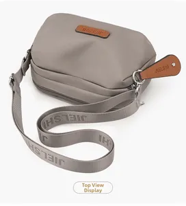 Top-down view of a grey nylon crossbody bag featuring an adjustable wide shoulder strap