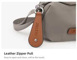 Close-up of durable leather zipper pull and brand logo on grey oxford fabric bag