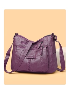 Detail view of deep purple soft faux leather crossbody bag with multiple zipper pockets