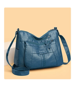 Close-up of a soft navy blue crossbody bag featuring multiple zipper pockets and texture