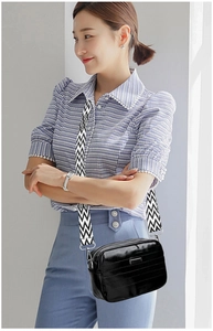 Detail of black leather crossbody bag with wave pattern wide shoulder strap
