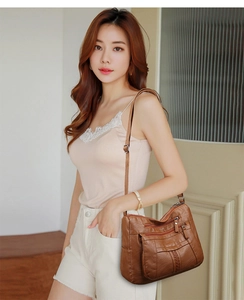 Detail view of brown washed leather crossbody bag with multiple zip compartments and strap