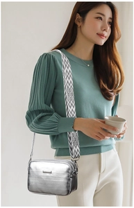 Silver metallic crossbody bag with geometric wide strap shown in an urban lifestyle scene
