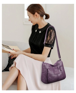 Detail of purple soft leather crossbody bag with multiple zipper pockets and texture