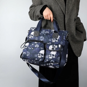 Navy blue tote bag with skull floral print and multiple utility pockets shown on model
