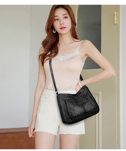 Detail view of black soft leather crossbody bag with multiple functional zippers