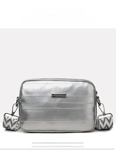 Close-up of silver quilted crossbody bag featuring a metal plate and wide patterned strap