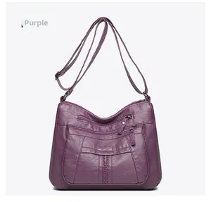 Detail view of purple washed leather crossbody bag with multiple zipper pockets