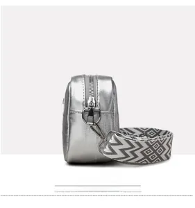 Detail view of silver metallic crossbody bag with black and white wavy pattern wide strap