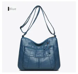 Detail view of the multi-zipper compartments and blue leather texture on women's crossbody bag