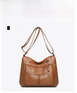 Front detail of brown washed soft leather crossbody bag with woven texture and multi-zippers