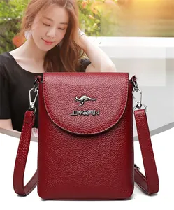 Close-up of red lychee textured leather crossbody bag with metal kangaroo logo