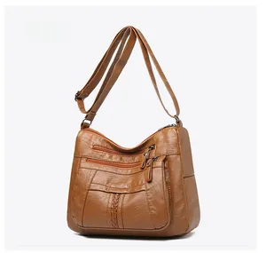 Detail of vintage brown leather crossbody bag with multi-zipper layers and woven texture