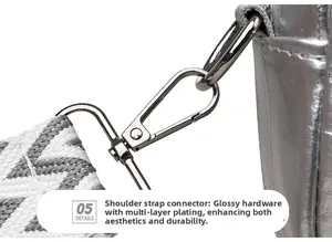Detail of silver crossbody bag featuring woven strap and polished metal hardware