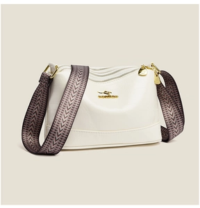 Detail view of cream crossbody bag with triple zipper pockets and wide woven strap