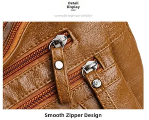 Close-up of smooth metal zippers and pebble textured brown leather on the crossbody bag