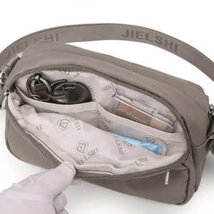 Functional interior of grey-brown nylon crossbody bag with dual pockets and logo lining