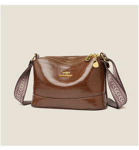 Three-layer zipper compartments of the dark brown leather bag with ethnic woven strap