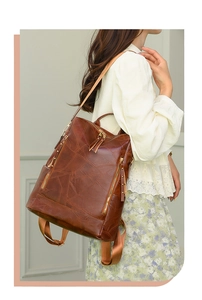 Detailed view of brown faux leather backpack featuring embossed leaf pattern and zippers