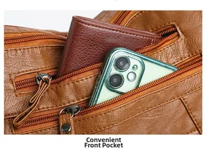 Detailed close-up of brown pebbled leather bag featuring multiple functional zipper pockets