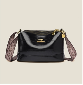 Close-up of gloss black crossbody bag with golden kangaroo logo and woven strap