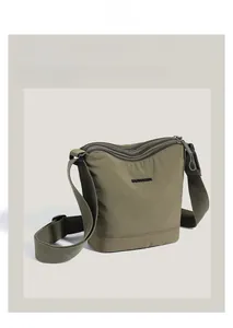 Detail view of the green nylon bucket bag featuring three functional zipper layers